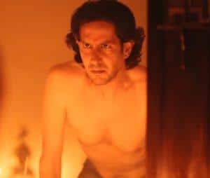 Imagen de un hombre con expresión pensativa en un ambiente cálido y oscuro.