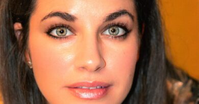 Rostro de mujer con ojos claros y expresión natural, en un entorno cálido y festivo.