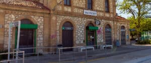 Imagen de un edificio histórico con fachada de piedra y ventanas con persianas verdes.