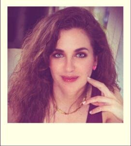 Mujer con cabello rizado y expresión soñadora, en un retrato artístico.