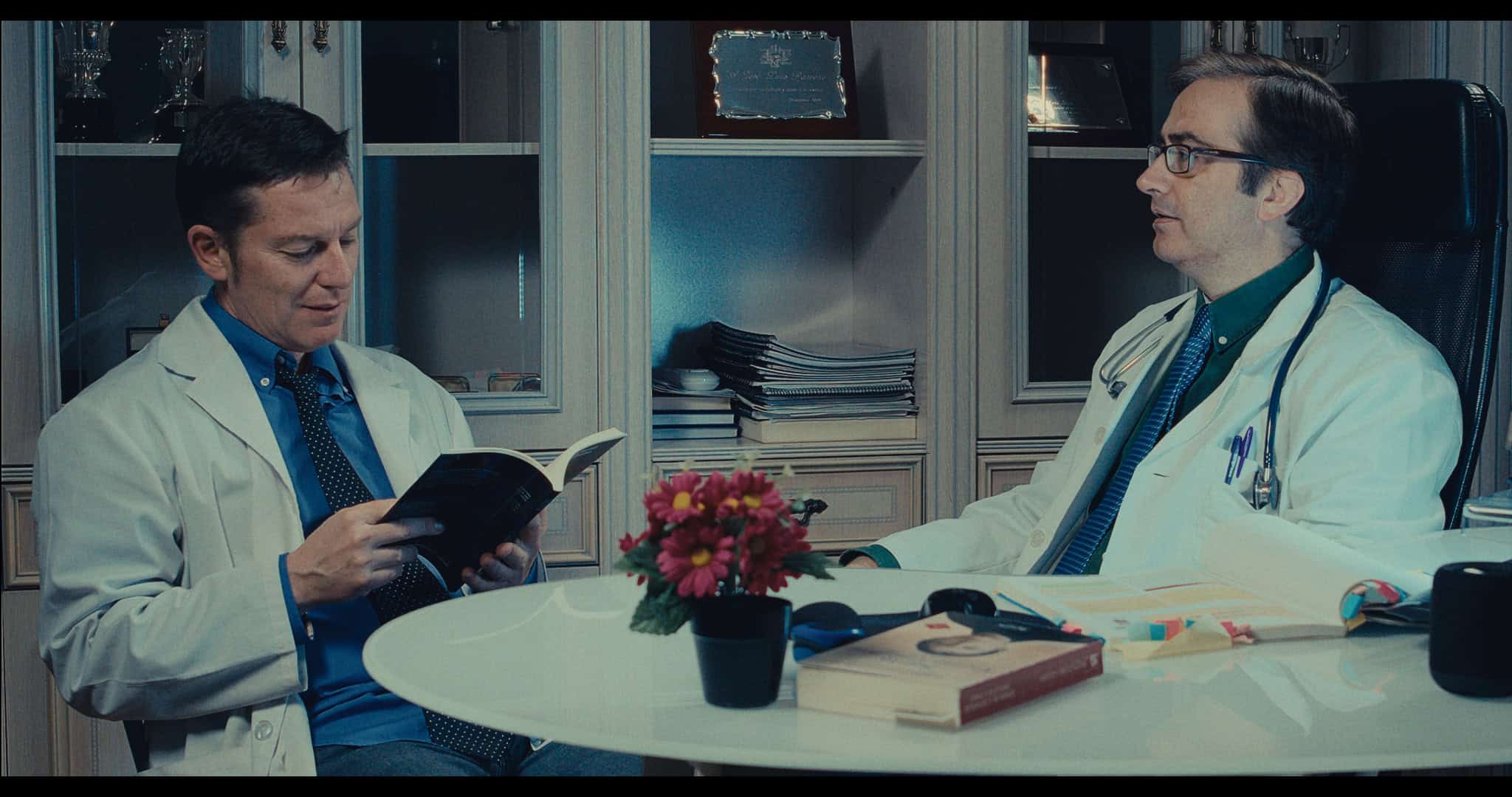 Escena de dos médicos conversando en una oficina, representando la temática cinematográfica y artíst.