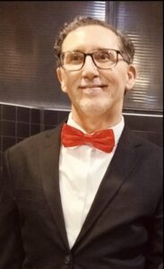 Retrato de un hombre con gafas y pajarita en evento cinematográfico.
